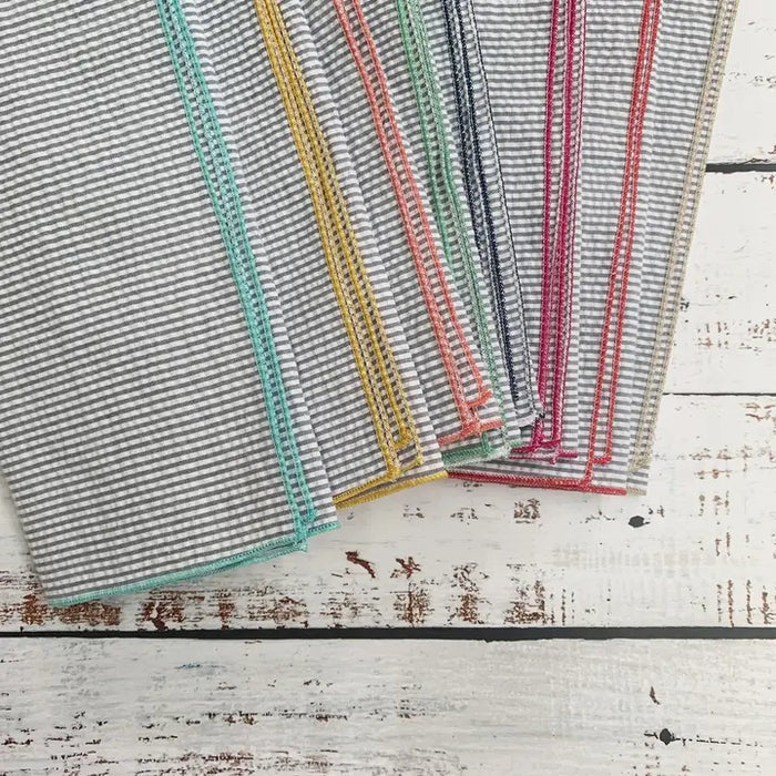 A set of DOT AND ARMY - GREY SEERSUCKER DINNER NAPKINS, each with colorful edging, is fanned out on a white background.