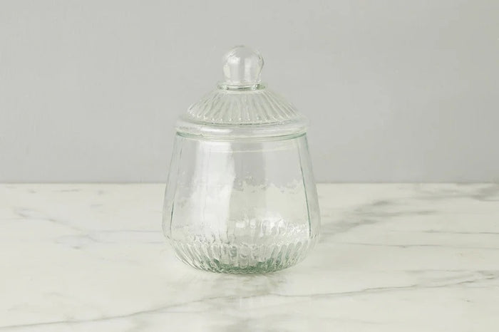 ETUHOME Bistro Glass Biscuit Jars with lids sit on a wooden tray, filled with snacks and orange-wrapped candies. The classic jar design by ETUHOME stands out against the softly blurred background.