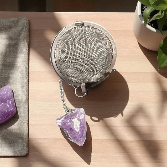 Metallic tea ball infuser with a chain on a wooden surface, Raven's Cauldron, 6 N Sandusky St, Delaware, OH 43015