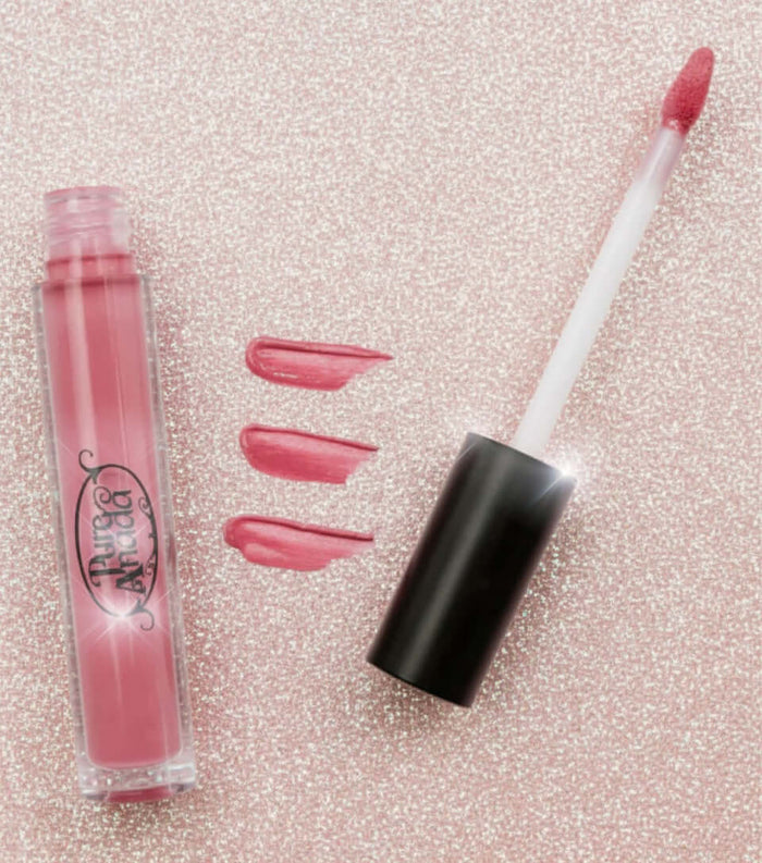 Pink lip gloss with applicator and swatches on a glittery pink background