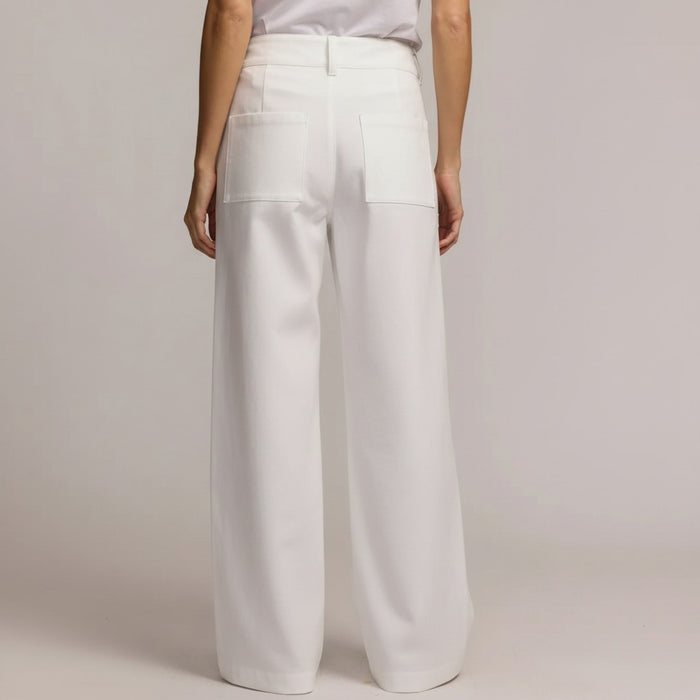 A person models the HINSON WU KELLY TRAVELERS TWILL PANT IN WHITE, featuring high-waisted, wide-leg stretch twill with large front pockets and double button closure—ideal travel-friendly style from HINSON WU.
