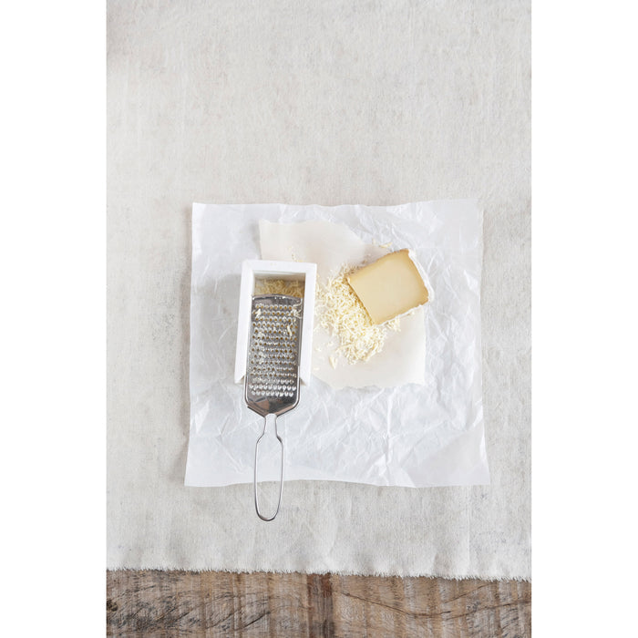 The CREATIVE COOP MARBLE AND STAINLESS STEEL GRATER, with its sleek handle and white marble rest, is shown from above, making it a stylish and modern addition to any kitchen countertop.