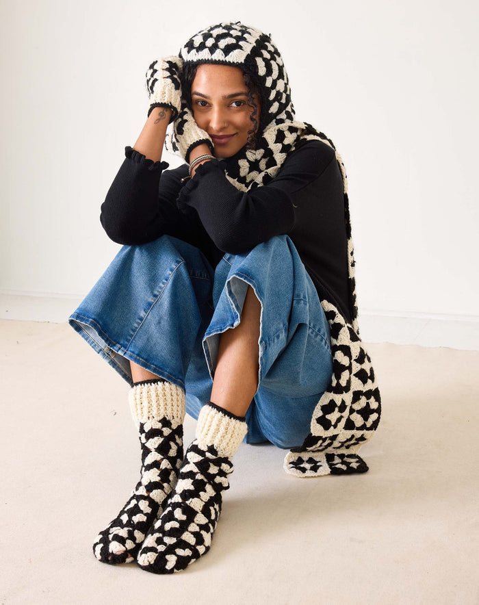 Introducing the MERSEA - LA PAZ CROCHET SLIPPER SOCKS by MERSEA: These hand-crocheted slipper socks feature a striking black and cream geometric design. The toes, heels, and cuffs are crafted in a solid cream shade, while the body showcases alternating black and cream sections—resulting in cozy socks you'll love to slip on.