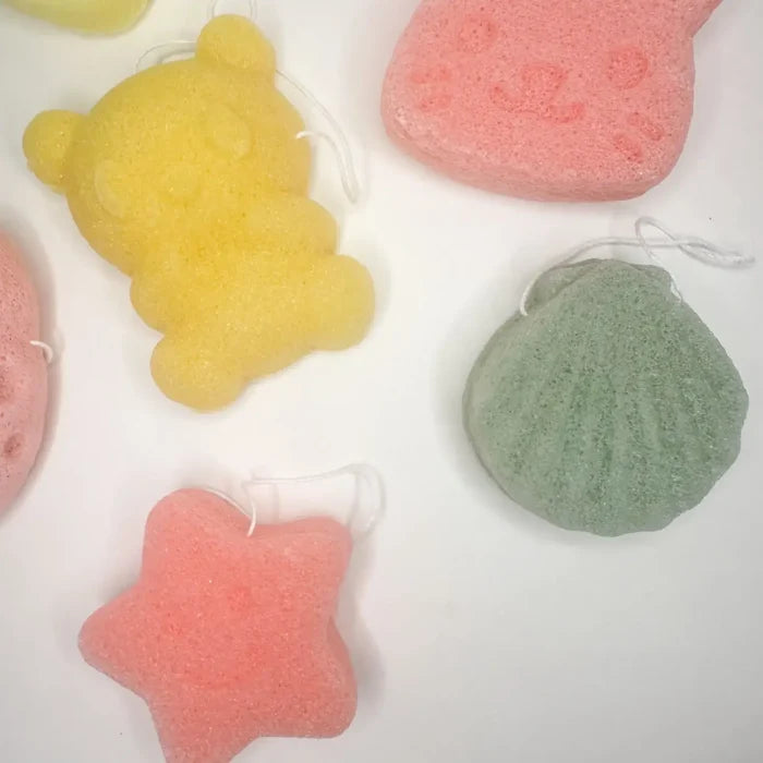 Colorful bath sponges shaped like a bear, star, and heart on a white background