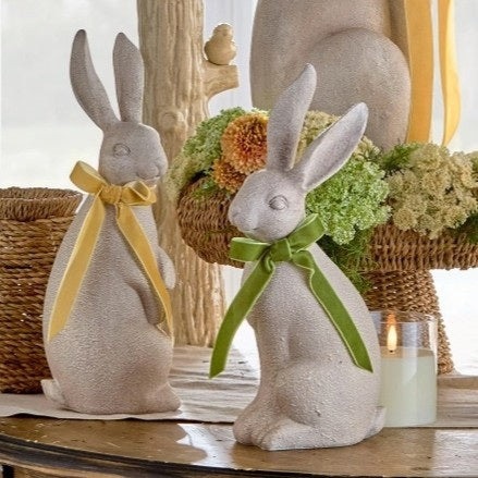 The RAZ IMPORTS RABBIT WITH BOW features two upright, concrete-look rabbit figurines with textured surfaces and yellow or green bows—charming rustic décor accents for any space.