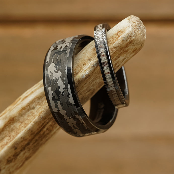 Showcased against a rich wooden background, The Sarge features two tungsten carbide rings displayed on a deer antler: the first is a bold digital camo ring with a distinctive black and gray camouflage pattern, while the second sports a slimmer profile with an eye-catching textured metallic finish—both perfect for elevating men’s fashion.