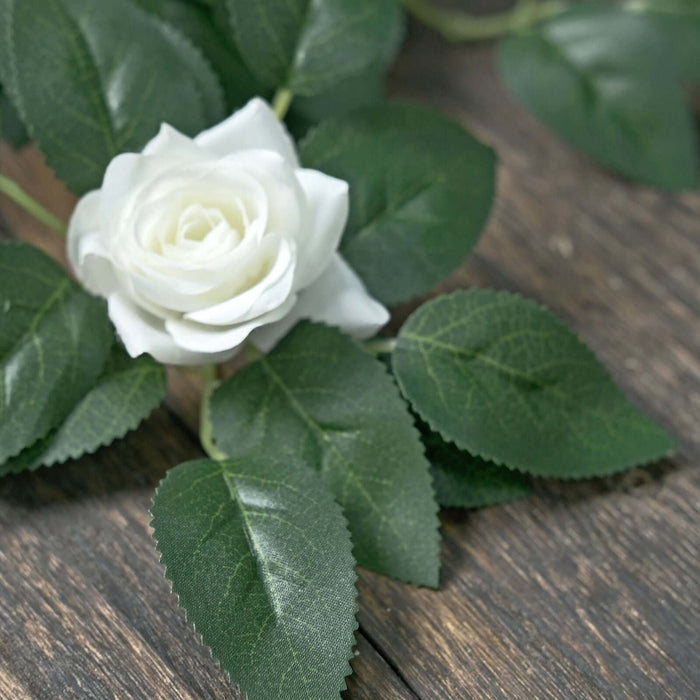 White rose with green leaves on wooden surface.