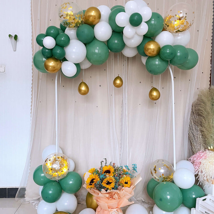 Green and white balloon arch with gold accents and floral arrangement in a festive setting.