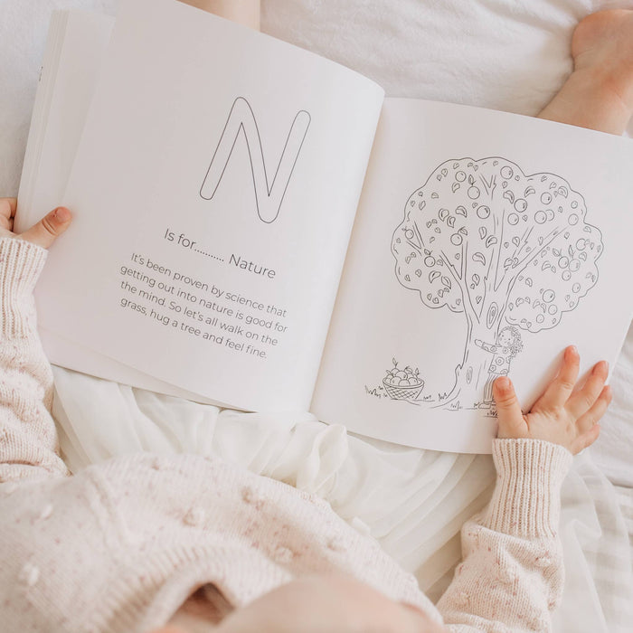 Person holding a coloring book open to a page with a tree illustration and text.