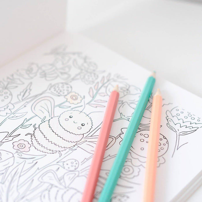 Coloring book with a hedgehog design and three colored pencils on a white surface.