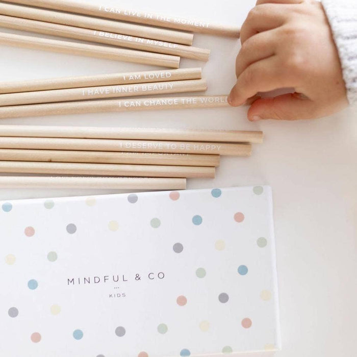 Affirmation Colouring Pencils with positive messages and child's hand, promoting joy and mindfulness.