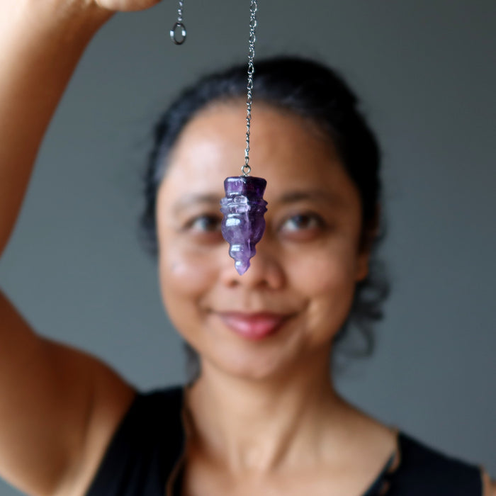 woman holding amethyst pendulum