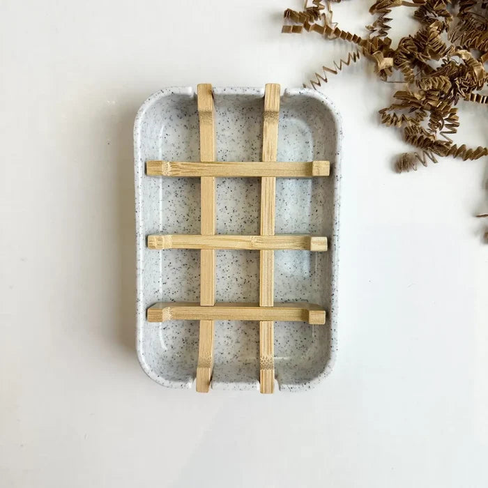 Speckled ceramic tray with woven wooden handle on a light background