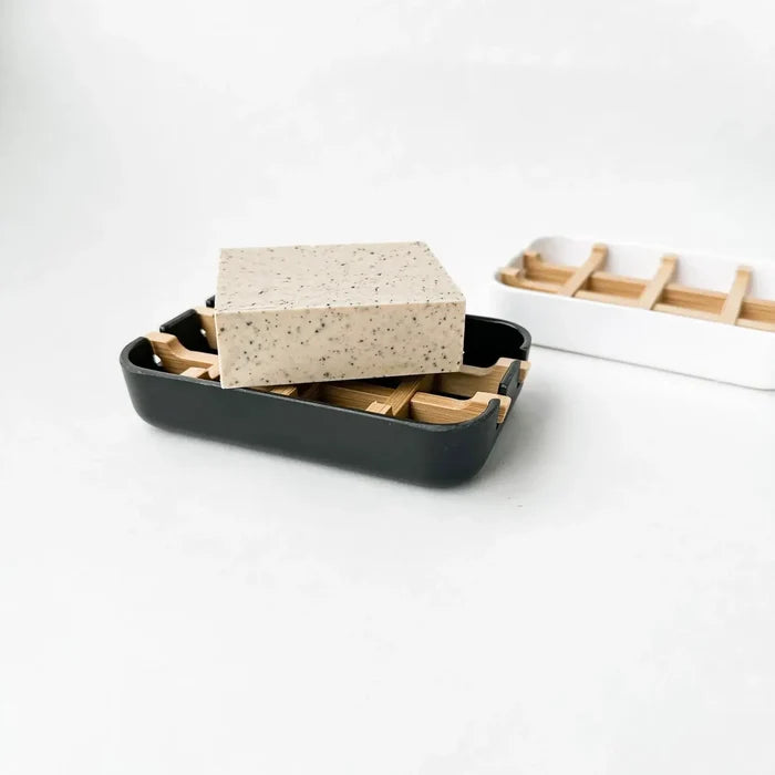 Sponge in a black dish with wooden compartments on a white background