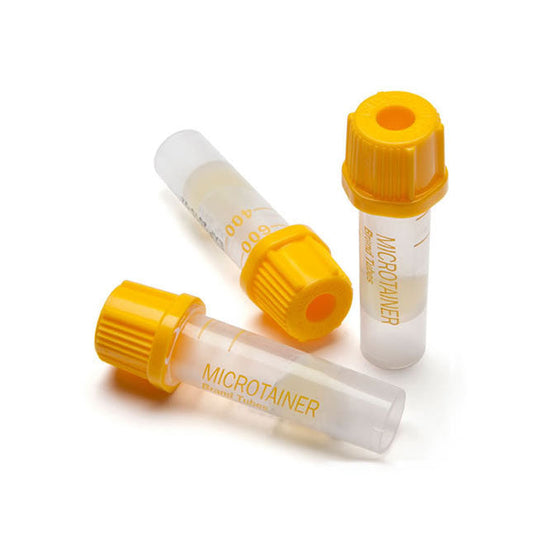Three MICROTAINER blood tubes, containing a light yellow liquid, rest on a white surface. The tubes have yellow screw caps.