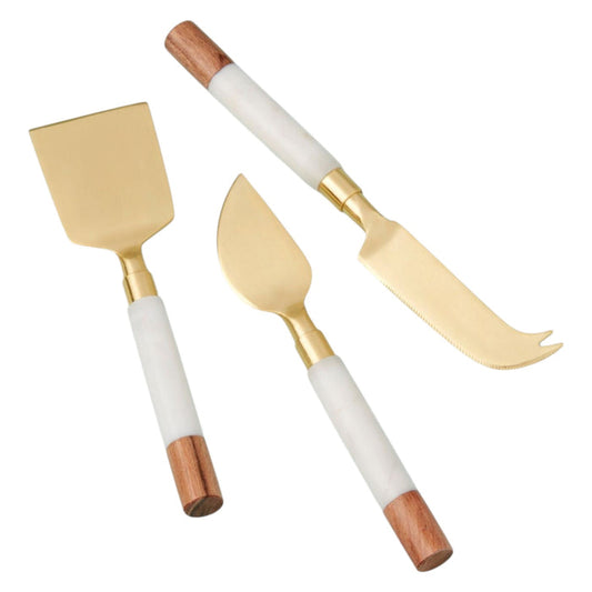 The BE HOME - GARNET CHEESE SET by BE HOME, INC features three elegant cheese knives with gold-toned blades and white handles accented with wood—perfect for elevating your charcuterie spread in both style and function.