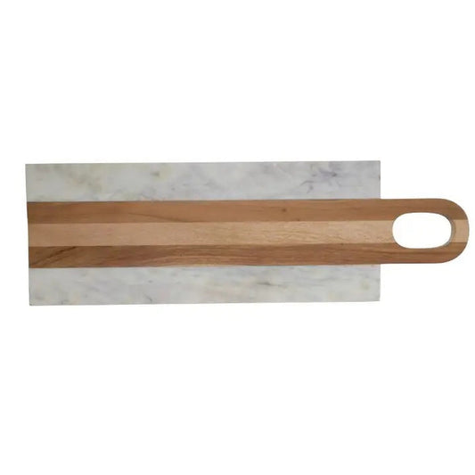 A kitchen scene features four BE HOME - MOA MARBLE & WOOD LONG BOARDS by BE HOME, INC, surrounded by herbs, sliced lemon, cherry tomatoes, olive oil, spice jars, a glass of wine, and bread on a beige countertop against a textured beige wall.