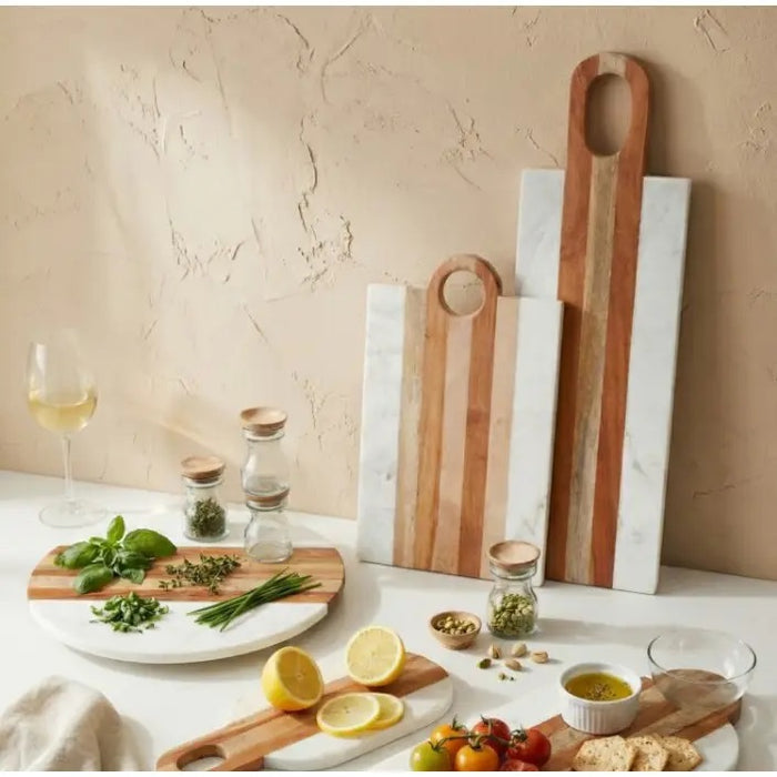 The BE HOME - MOA Marble & Wood Rectangular Board by BE HOME, INC features alternating light wood and white marble stripes with a circular handle, making it a stylish and ethical addition to your home goods collection.