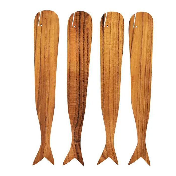 The BE HOME - TEAK WHALE SPREADERS by BE HOME, INC rest on a round white marble cutting board with a hole at the top, displayed on a wooden surface.