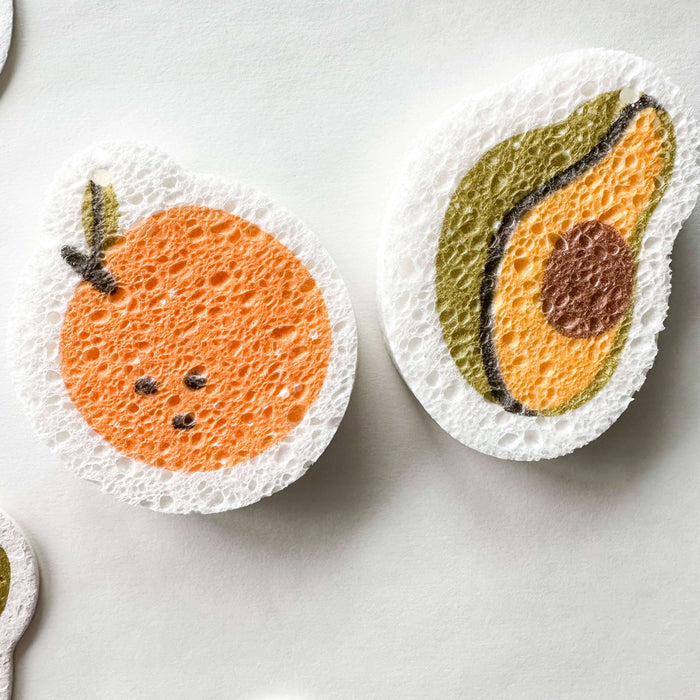 Fruit-themed dishcloths shaped like an orange and an avocado on a white background