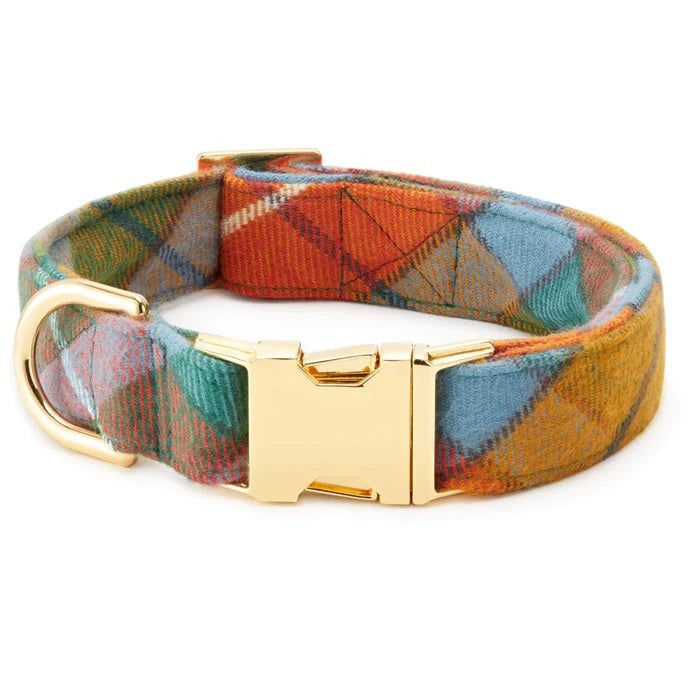 Two BUCHANAN PLAID DOG COLLARS from THE FOGGY DOG, each featuring gold metal buckles and D-rings, showcase a vibrant plaid pattern in blue, orange, yellow, and pink tones on a white surface.