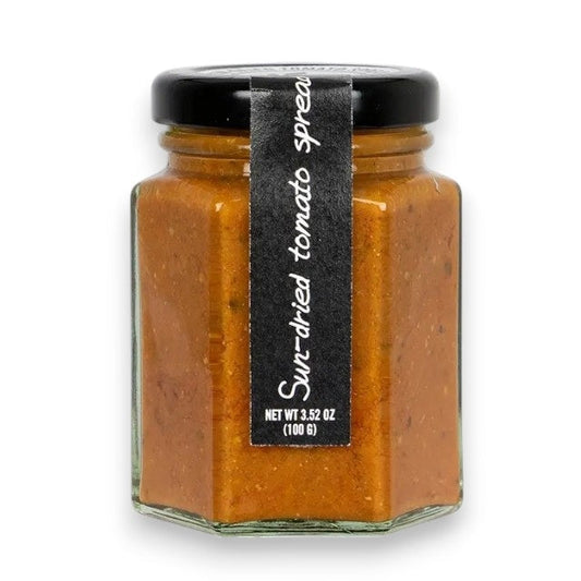 A hexagonal glass jar of RITROVO’s CASCINA ROSSA Sun-Dried Tomato Spread, expertly crafted in Italy with extra virgin olive oil. The jar features a black lid and a vertical black label stating “Sun-dried tomato spread.” Net weight: 3.52 oz (100g).
