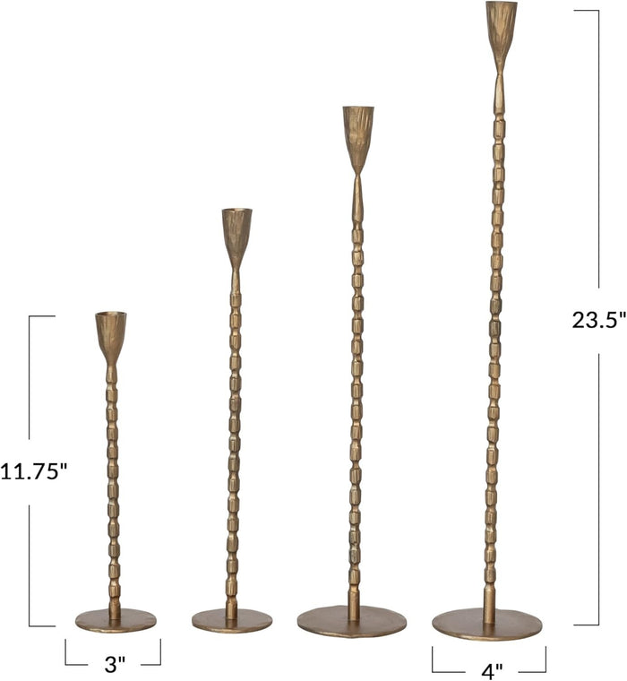 The CREATIVE COOP CAST IRON TAPER HOLDER IN BRASS FINISH, LARGE, features a tall, slender design with a textured segmented stem and round base, perfect for displaying a single taper candle.