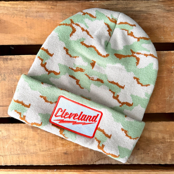 Green and white patterned beanie with a red 'Cleveland' patch on a wooden surface