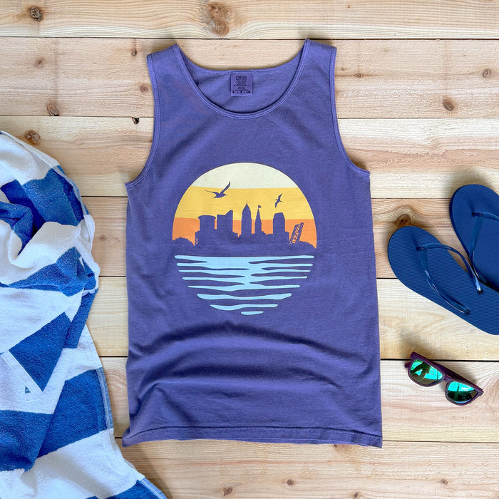 Purple tank top with a sunset design on a wooden surface with beach accessories.