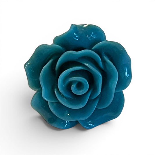 A teal resin lapel flower pin by CLIFTON WILSON is displayed on a white surface. This elegant accessory features a gold clasp, perfect for formalwear.