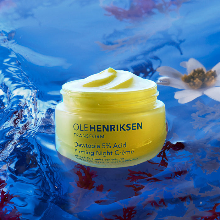 Stylized image of open packaging of Dewtopia 5% Acid Firming Night Crème shown on a blue background with white and red flowers.