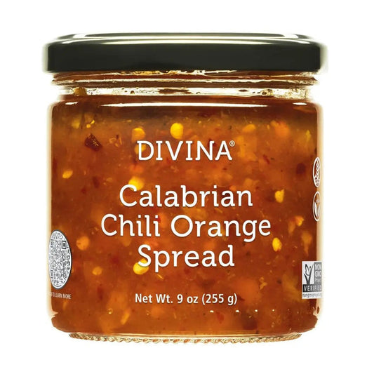 Two tortillas topped with shredded meat, red and green cabbage slaw, and cilantro sit on a wooden board with lime wedges on the side, placed on a purple cloth. A drizzle of DIVINA - CALABRIAN CHILI ORANGE SPREAD by DIVINA adds a sweet and spicy kick, perfectly complementing the vibrant flavors.