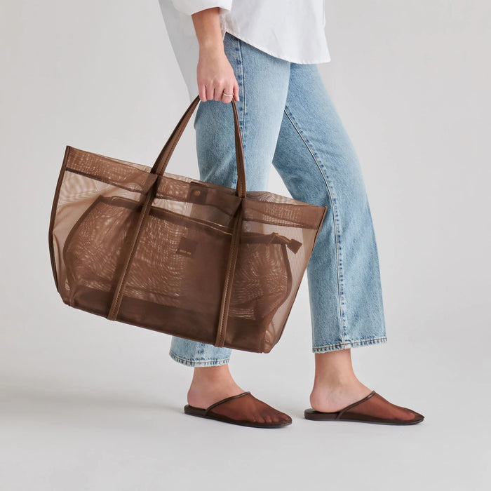 The DOLCE VITA - GENI Mesh Flats in Chocolate are chic brown slip-on mules with a low heel and flat sole, inspired by ballet flats, shown against a light gray background.