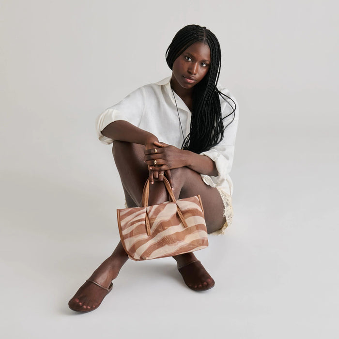 The DOLCE VITA - GENI Mesh Flats in Chocolate are chic brown slip-on mules with a low heel and flat sole, inspired by ballet flats, shown against a light gray background.