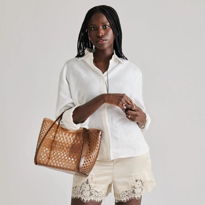 The DOLCE VITA - TOP HANDLE WHISKEY JELLY HANDBAG features a brown lattice design, curved handles, and “dolce vita” embossed on the front—a stylish, see-through tote perfect for vacations.