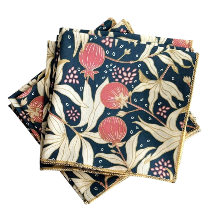 The DOT AND ARMY Gooseberry Cocktail Napkin features a red, cream, and dark green floral and pomegranate print with yellow-stitched edges—sustainable napkins ideal for any gathering.