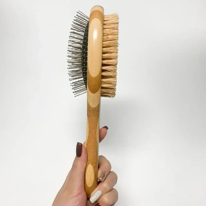Hand holding a wooden brush with bristles on a white background