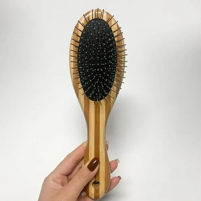 Wooden hairbrush with black bristles held by a hand on a white background