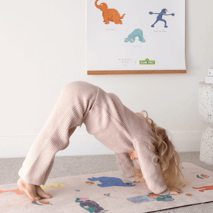 Child practicing yoga pose with Double-sided Sesame Street Yoga Poses Print in the background.
