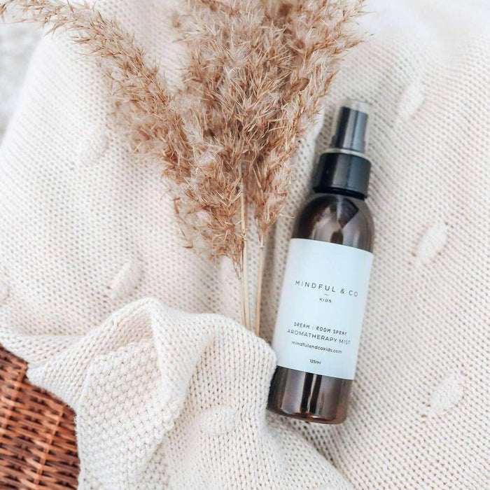 Bottle of Mindful & Co room spray on a textured surface with pampas grass