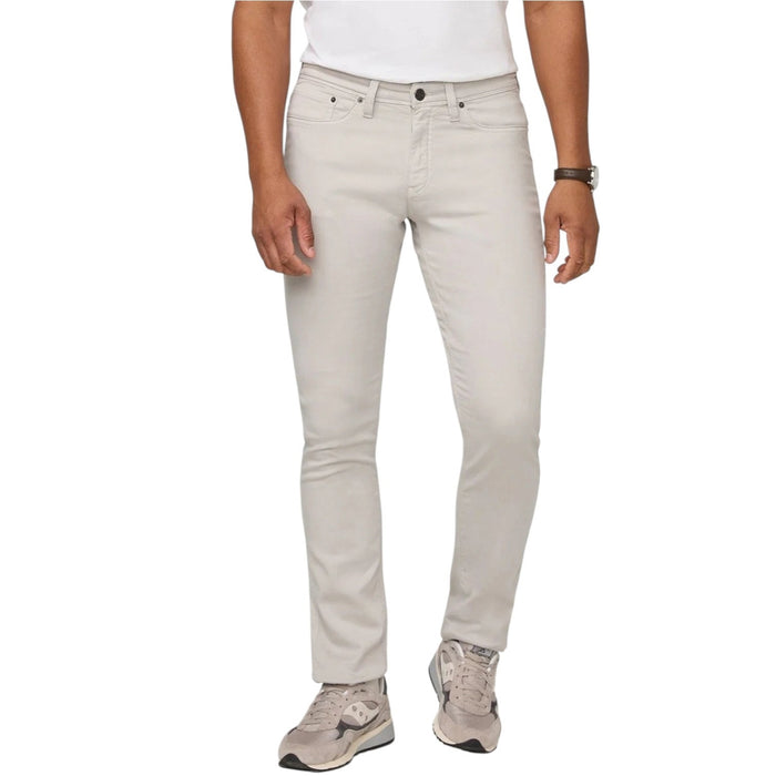 A person stands facing forward on a plain light background, wearing DUER NO SWEAT ATHLETIC TAPER PANTS IN MIST and matching light gray sneakers, feet slightly apart.
