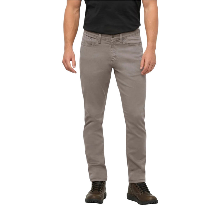 Close-up of the back of a person wearing DUER No Sweat Athletic Taper Pants in Stone, featuring two back pockets and a tan leather DUER patch on the waistband. They're also wearing a black shirt.
