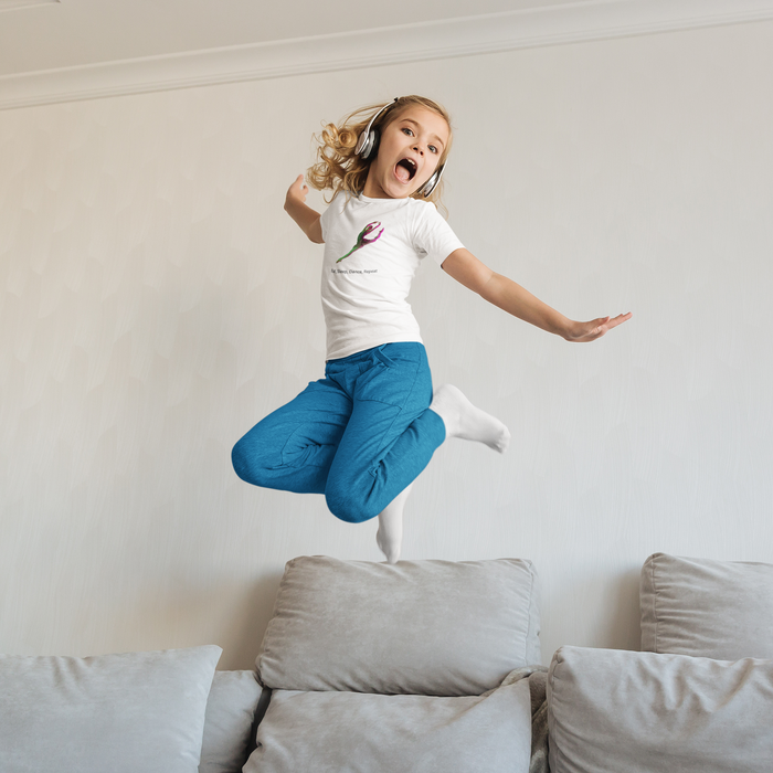 Child jumping on a couch wearing a white t-shirt with a pink design and blue pants.