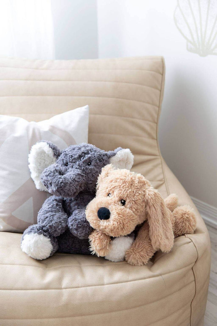 Eleanor The Weighted Elephant and a plush dog toy on a cozy couch, perfect companions for comfort and calm.
