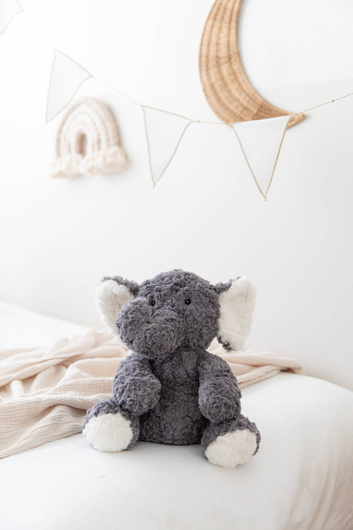 Eleanor The Weighted Elephant plush toy sitting on a bed, designed for comfort and relaxation for children.