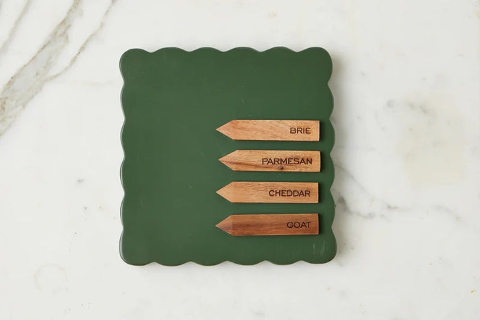 The ETUHOME Green Square Scalloped Cheese Board with Markers displays six savory herb tarts arranged in a circle around a glass dip bowl, resting on a beige napkin with two forks on a marble surface.