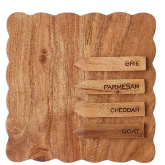 Three small savory tarts, paired with green leaves, are displayed on the ETUHOME Natural Square Scalloped Cheese Board with Markers, set against a floral-patterned background.