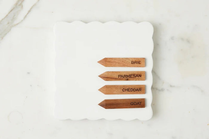 The ETUHOME White Square Scalloped Cheese Board with Markers features a chic plate and four wooden cheese markers—BRIE, PARMESAN, CHEDDAR, and GOAT—ideal for stylishly serving your favorite cheeses.