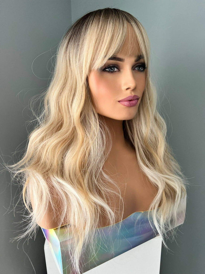 Woman wearing a blonde wig against a plain background