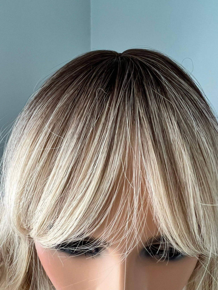 Blonde wig with bangs on a neutral background